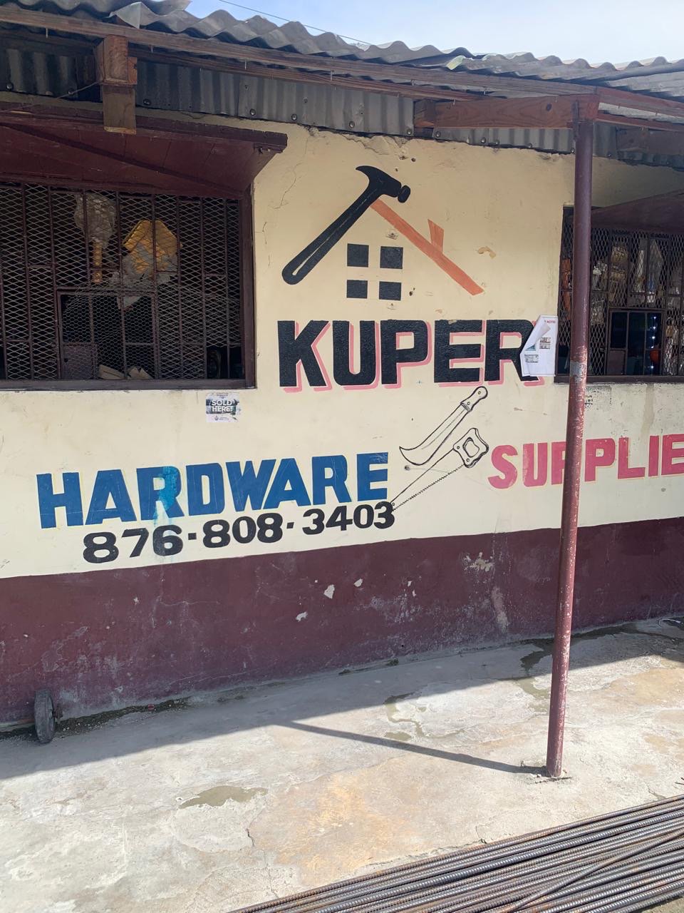 The Kuper Hardware storefront on Main Street, Bog Walk, painted with the phone number 876-808-3403